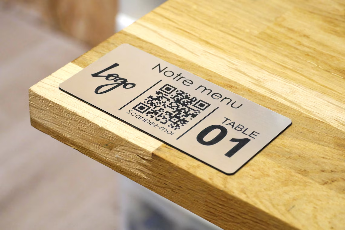 Restoran masasına sabitlenmiş metal QR menü etiketi